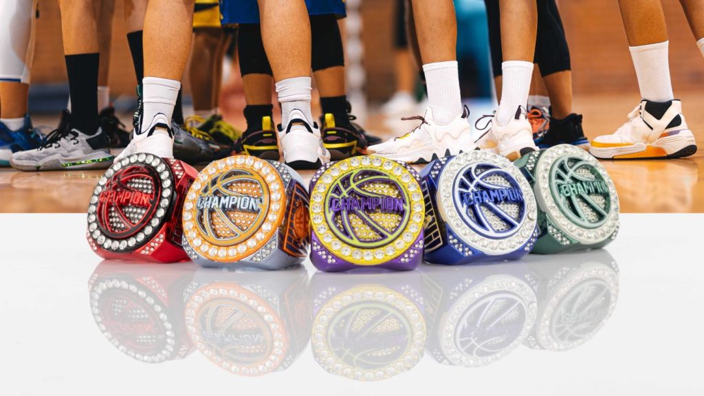 A hand holds several custom youth championship awards featuring vibrant team colors.